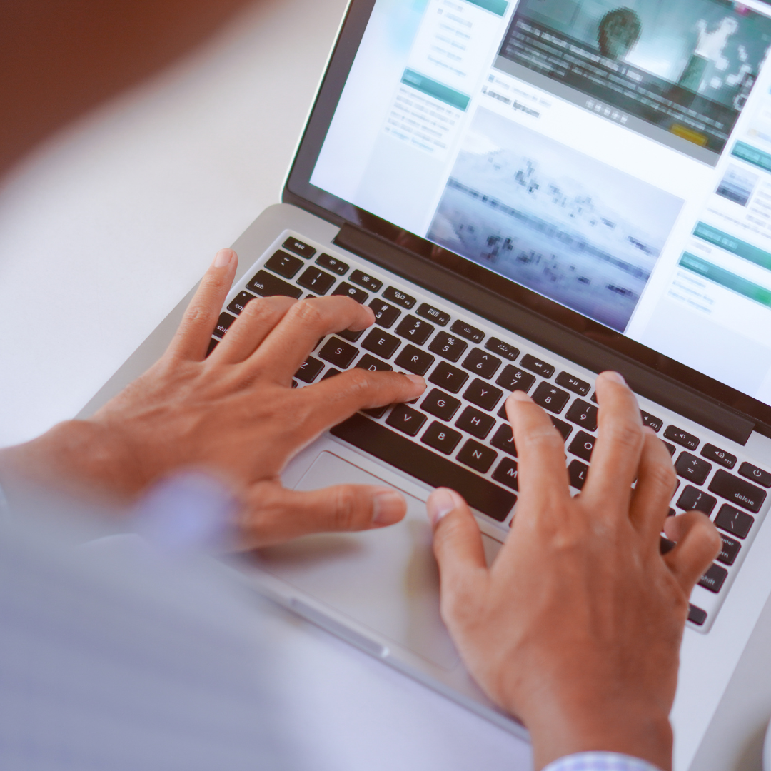 Person tippt auf einer Laptop Tastatur und navigiert durch eine Webseite mit Artikeln und Bildern. Symbolisiert digitales Arbeiten, Online Recherche oder Content Erstellung.